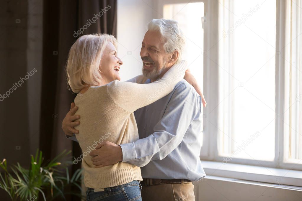 Happy old retired romantic couple dancing laughing in living room