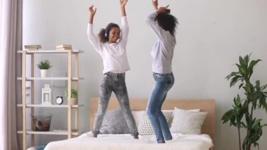 Karışık ırk anne ve kızı yatakta müzik dans keyfini çıkarın