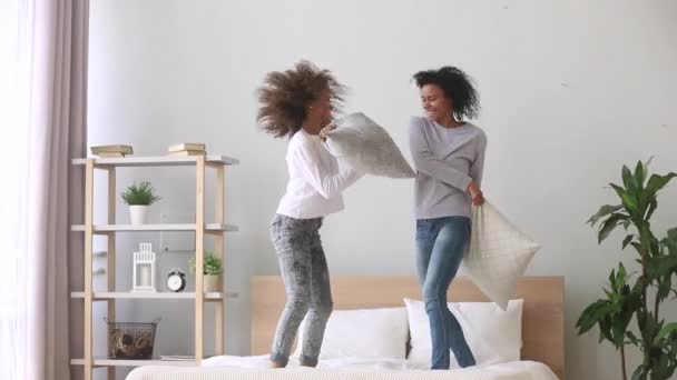 Daughter and mother play fighting with pillows standing on bed — Stock Video