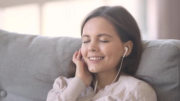 Vrouw rusten op de Bank luisteren muziek via koptelefoon thuis — Stockvideo