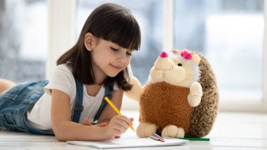 Sevimli çocuk kız yerde yatan oyuncak ile çizim oynarken