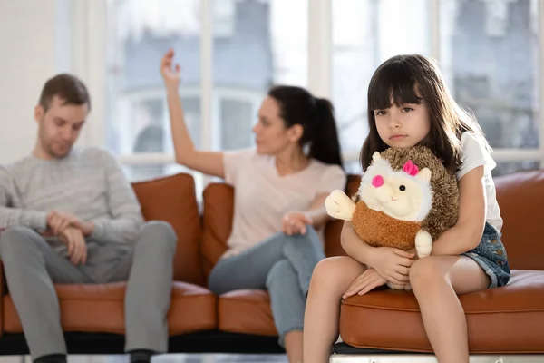 Triste hija sosteniendo juguete sentimiento herido acerca de padres discutiendo — Foto de Stock