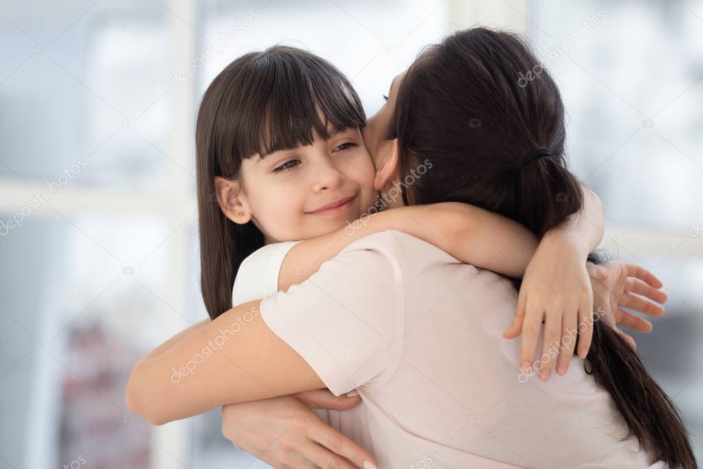 Happy cute child girl hugging mother foster parent feel connection