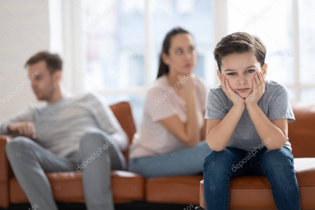 Upset child boy looking at camera sad about parents fights