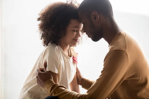 Loving African American father and daughter hugging, touching foreheads — Stock Photo, Image