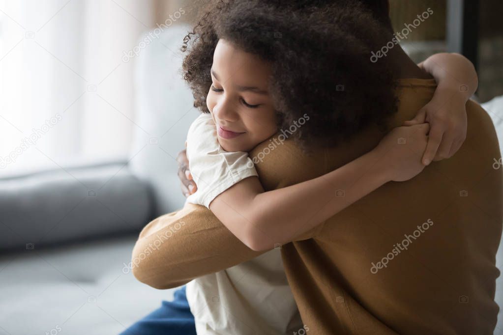 Happy cute African American daughter and father hugging, feeling love