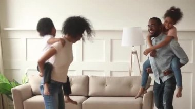 Afrikalı anne evde eğlenen küçük çocuklar arkasında taşıyan