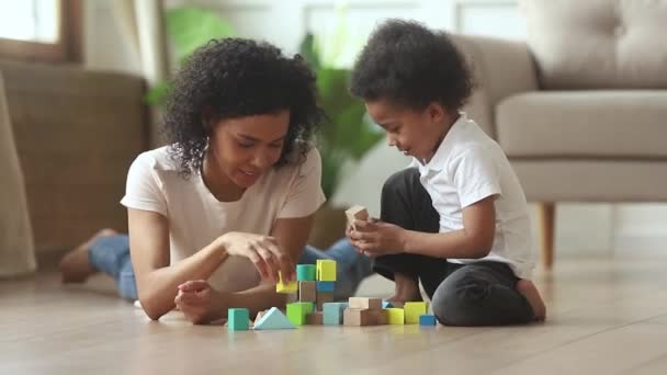 Africano madre hijo jugar en piso con juguete bloques conjunto — Vídeo de stock