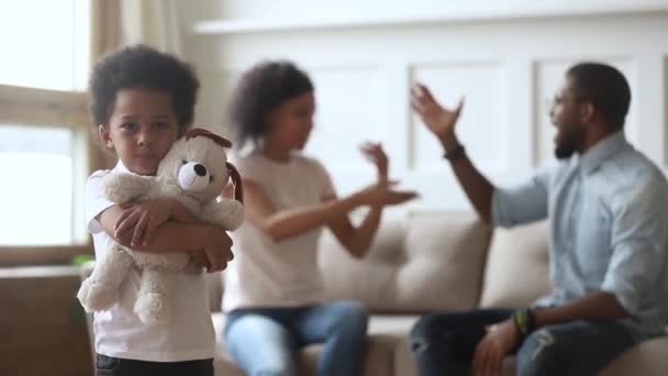 Infeliz poco africano hijo abraza juguete mientras padres peleando — Vídeo de stock