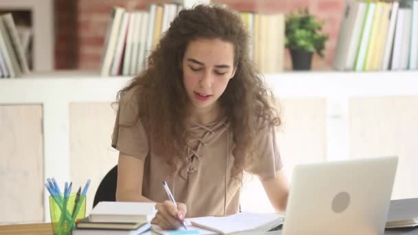 Mladá dívka seděla v knihovně a připravila se na univerzitní sezení — Stock video