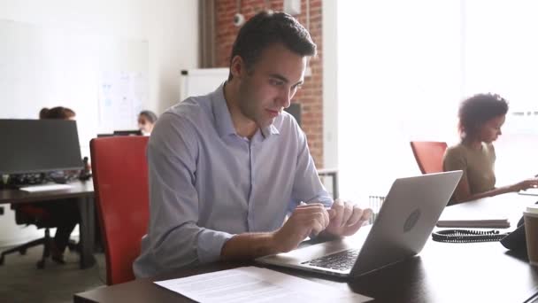 Працівник середнього віку дивиться на договірний документ, що вводиться на ноутбук — стокове відео