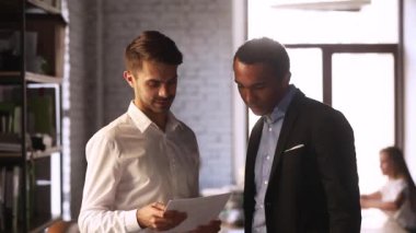 Çok ırklı iş arkadaşları iş günü boyunca mali rapor evrak tartışıyor konuşuyor