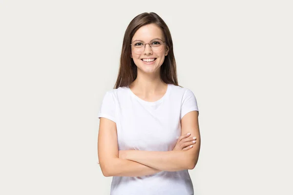 Smiling millennial girl in glasses standing with arms closed — Stock Photo, Image