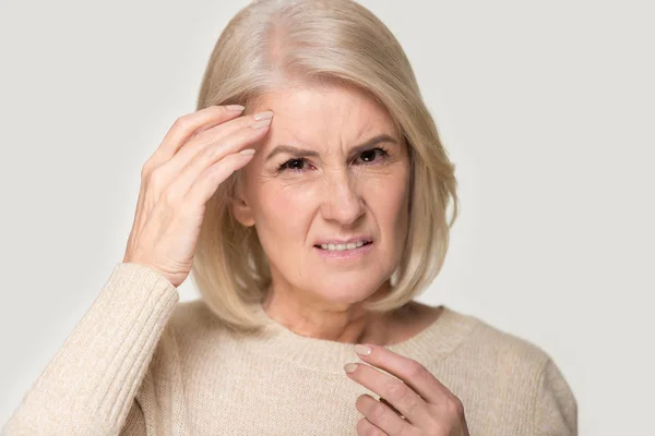 Unhealthy senior woman isolated on studio background having migraine — Stock Photo, Image