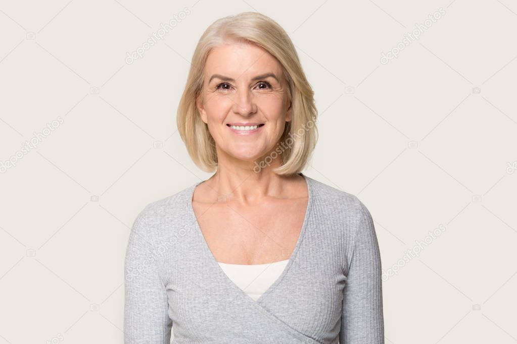 Headshot of smiling senior woman isolated on grey background