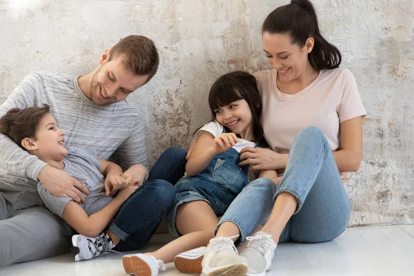 Happy parents and cute children playing tickling sit on floor — Stock Photo, Image