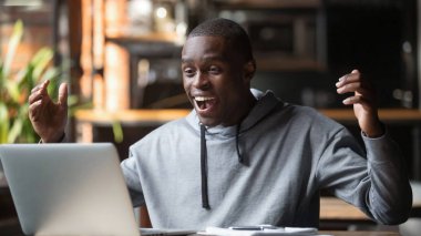 Overjoyed Afrikalı adam dizüstü bilgisayarda büyük haber online bakmak okuyun