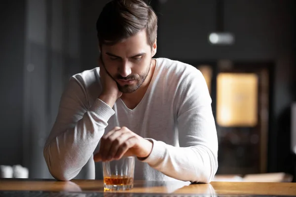 Upset man drinker alcoholic sitting with glass drinking whiskey alone