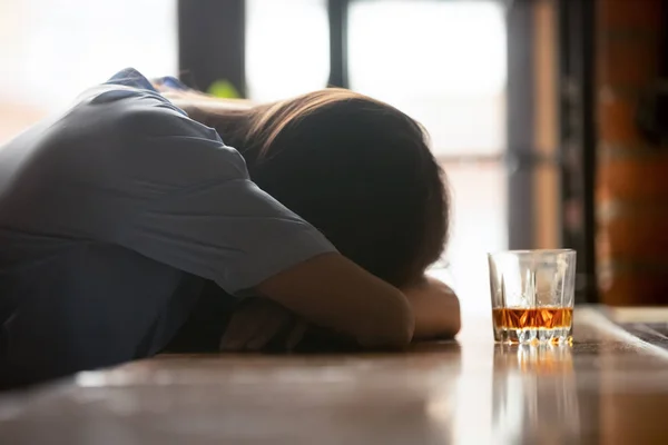 Opilá mladá žena spící na baru u skleničky whisky — Stock fotografie