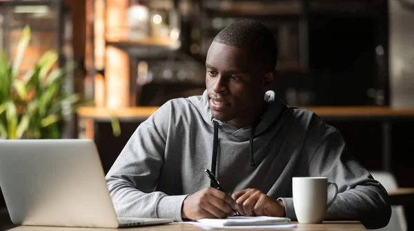 Focused young man studying with laptop make notes in cafe — Stock Photo, Image