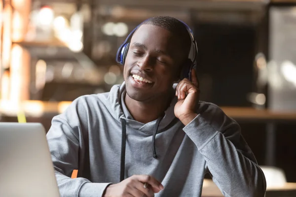 Relaxed young black man wear wireless headphones enjoy good music — Stock Photo, Image