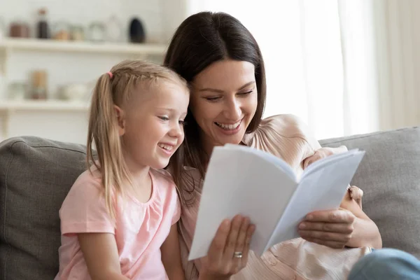 Весела мати і дочка сидять на дивані читаючи казку — стокове фото