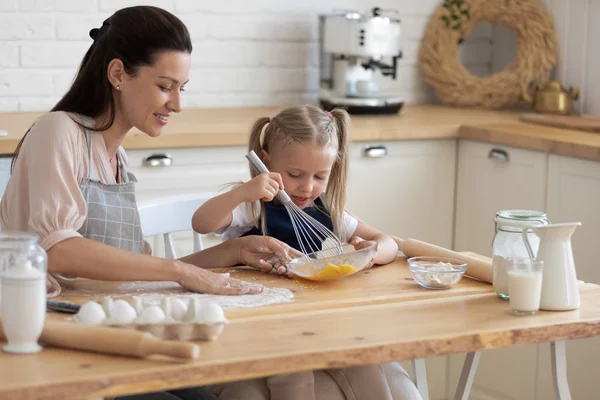 Little girl and mother cooks pie together in kitchen — Stock Photo, Image