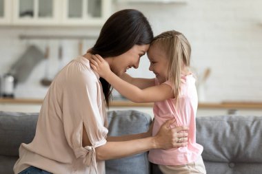 Mother daughter looking at each other touch foreheads feeling love