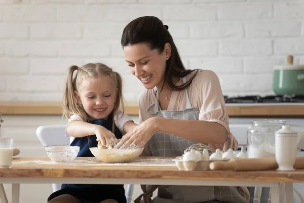 La madre e la figlia piccola cucinano insieme mescolano la massa per pasta — Foto Stock