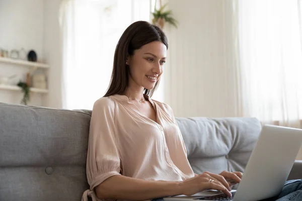 Belle femme assise sur le canapé à l'aide d'un ordinateur — Photo