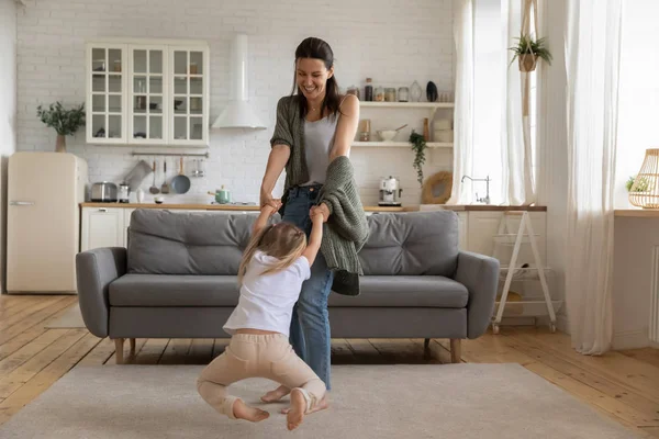 Krásná žena se točí v kruhu malá dcera v obývacím pokoji — Stock fotografie