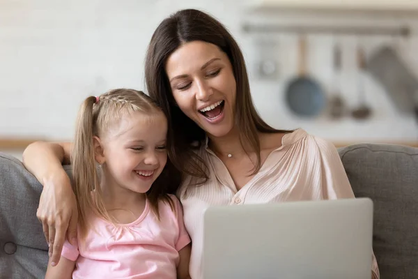 Mãe e pequena filha olhando para a tela do computador apreciando desenhos animados — Fotografia de Stock