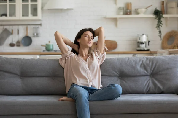 Жінка насолоджується вільним часом, відпочиваючи на дивані вдома — стокове фото
