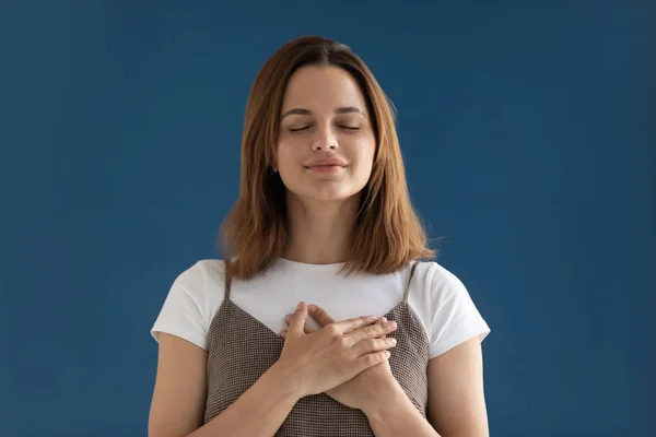 Portret van dankbaar hoopvolle vrouw vasthouden van handen op de borst geïsoleerd — Stockfoto
