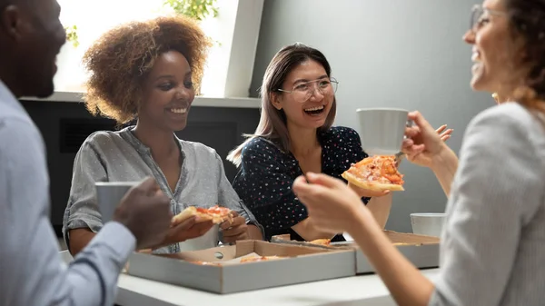 Joyful Friendly mångkulturellt team ha kul att äta pizza tillsammans — Stockfoto