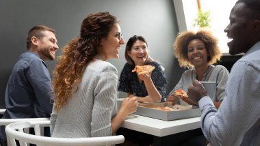 Neşeli çok ırklı iş ekibi insanlar birlikte pizza yeme eğleniyor