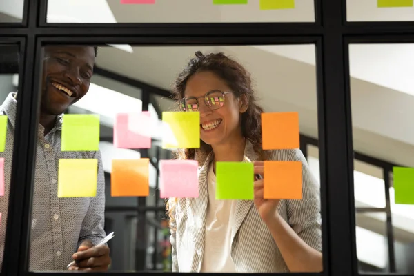 Duas pessoas de equipe feliz diversificada trabalhando em conjunto com notas pegajosas — Fotografia de Stock