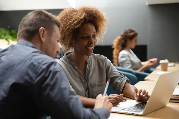 African woman mentor training caucasian intern helping colleague with software