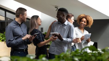 Mutlu dostu çok ırklı iş ekibi ofiste ayakta gülerek konuşuyor