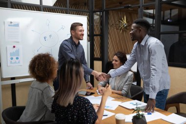 Mutlu kafkas patronu el sıkışma erkek Afrikalı çalışan takım toplantısında