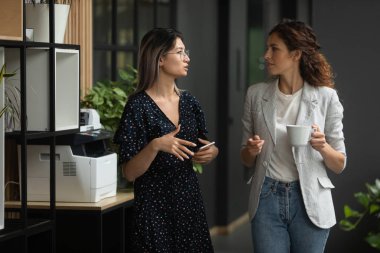 Ofis alanında yürüyüş konuşan ciddi çeşitli kadın meslektaşları
