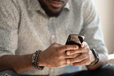 Akıllı telefonu tutan genç Afro-Amerikan adamı kapatın.