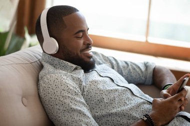 Mutlu afro-Amerikan adam evde kanepede yatan.