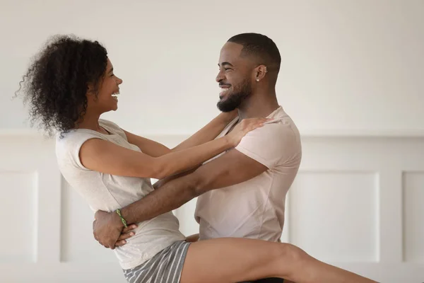 Feliz afroamericano hombre sosteniendo alegre sonriente esposa . — Foto de Stock