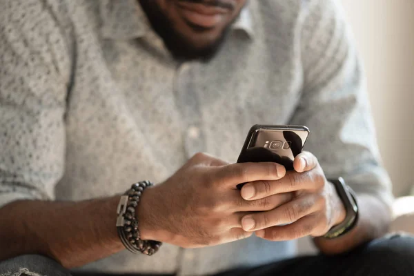 Крупним планом молодий афроамериканський чоловік тримає смартфон . — стокове фото