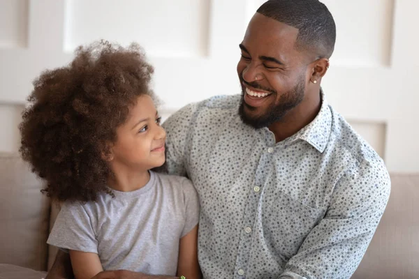 Überglücklich afrikanisch-amerikanischer Mann kuschelt kleine süße lockige Tochter. — Stockfoto