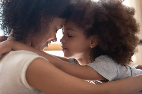 Küçük sevimli kızı ile alınlarına dokunan karışık ırk anne. — Stok fotoğraf