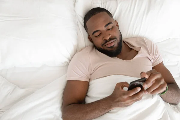 Rested african american man waking up at comfortable bed. — Stock Photo, Image