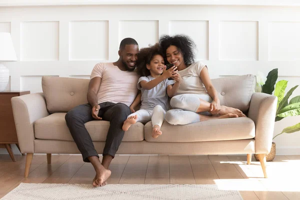 Lächelndes kleines Mischlingsmädchen zeigt lustiges Video am Telefon. — Stockfoto