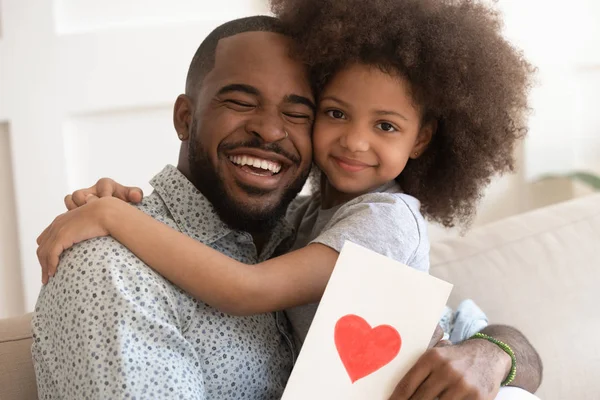 Emocionado papá negro feliz sosteniendo linda hija y tarjeta de felicitación . — Foto de Stock